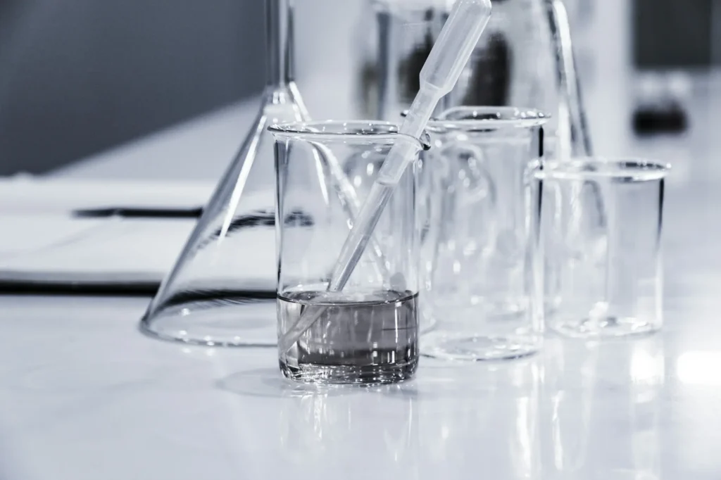 Zestaw naczyń laboratoryjnych ze szkła, w tym zlewka z pipetą.